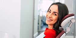 Woman in red shirt smiling in treatment chair