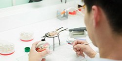 a technician working on a pair of dentures