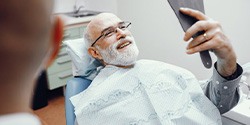 a patient checking his smile with a mirror