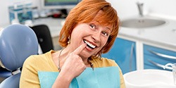 Happy dental patient pointing at her smile
