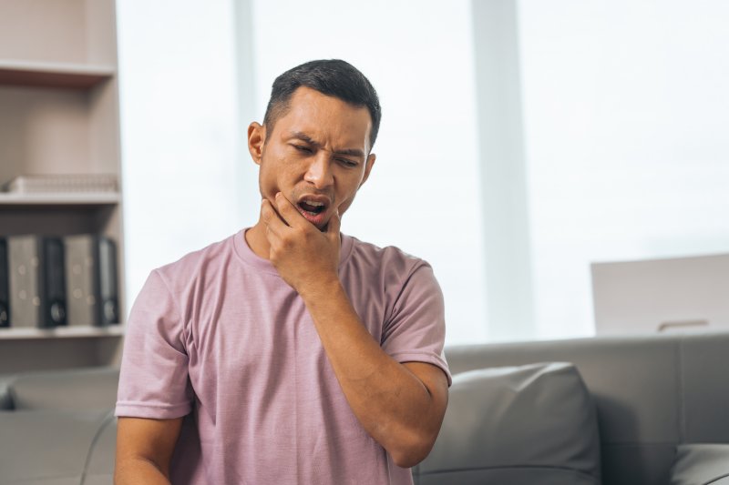 a man holding his jaw due to tooth sensitivity